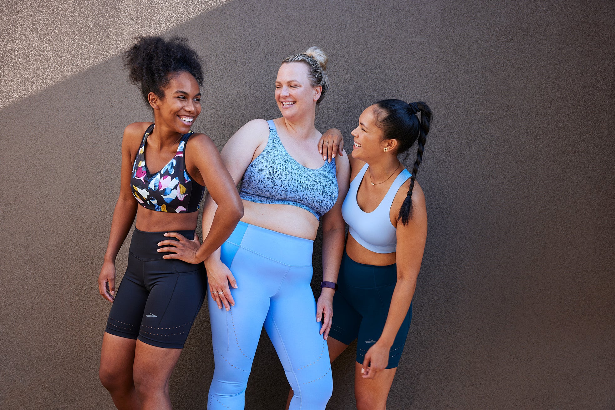 picture of womens in sports bras and athletic bottoms smiling.