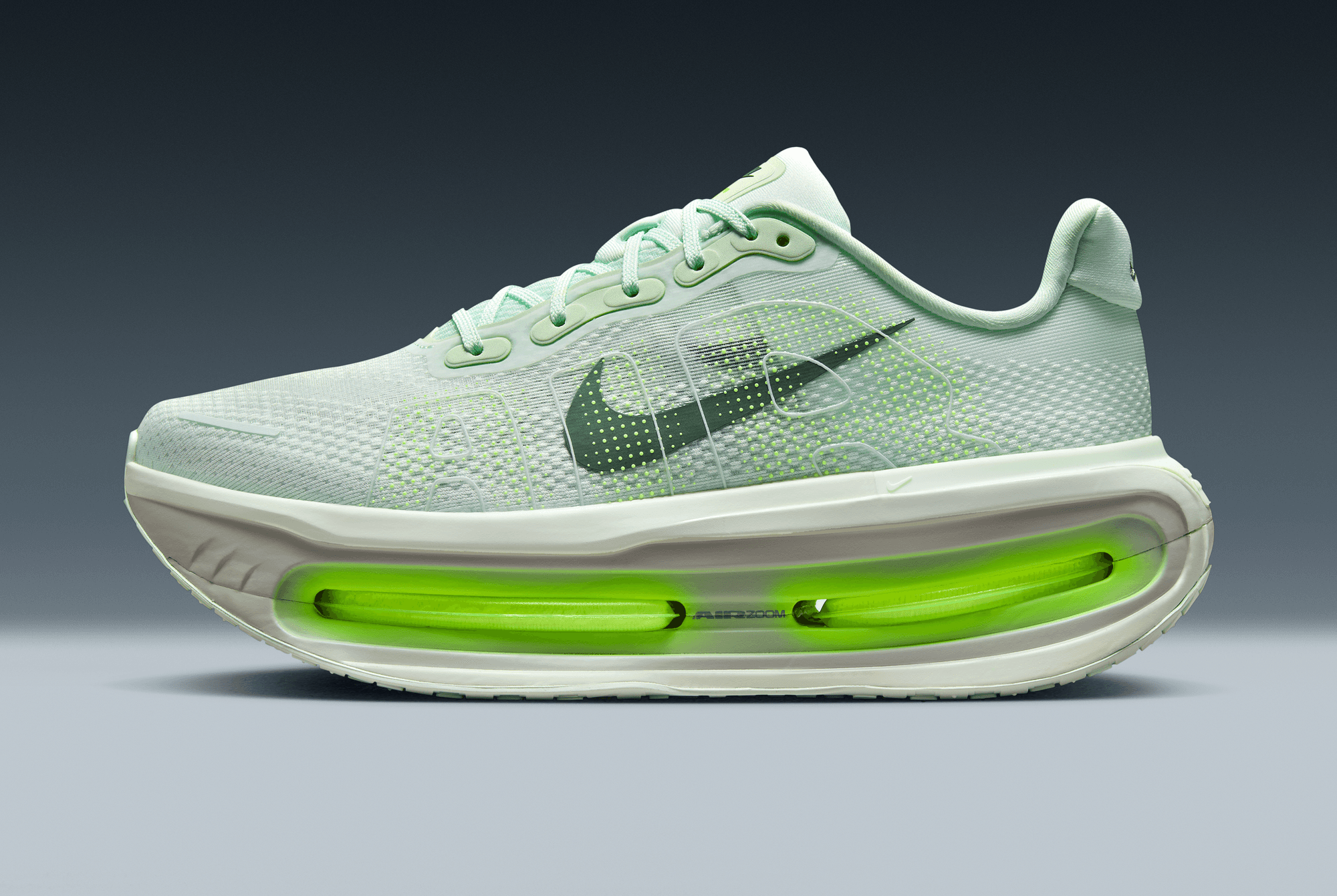 Light blue running shoe with green sole on a gray background