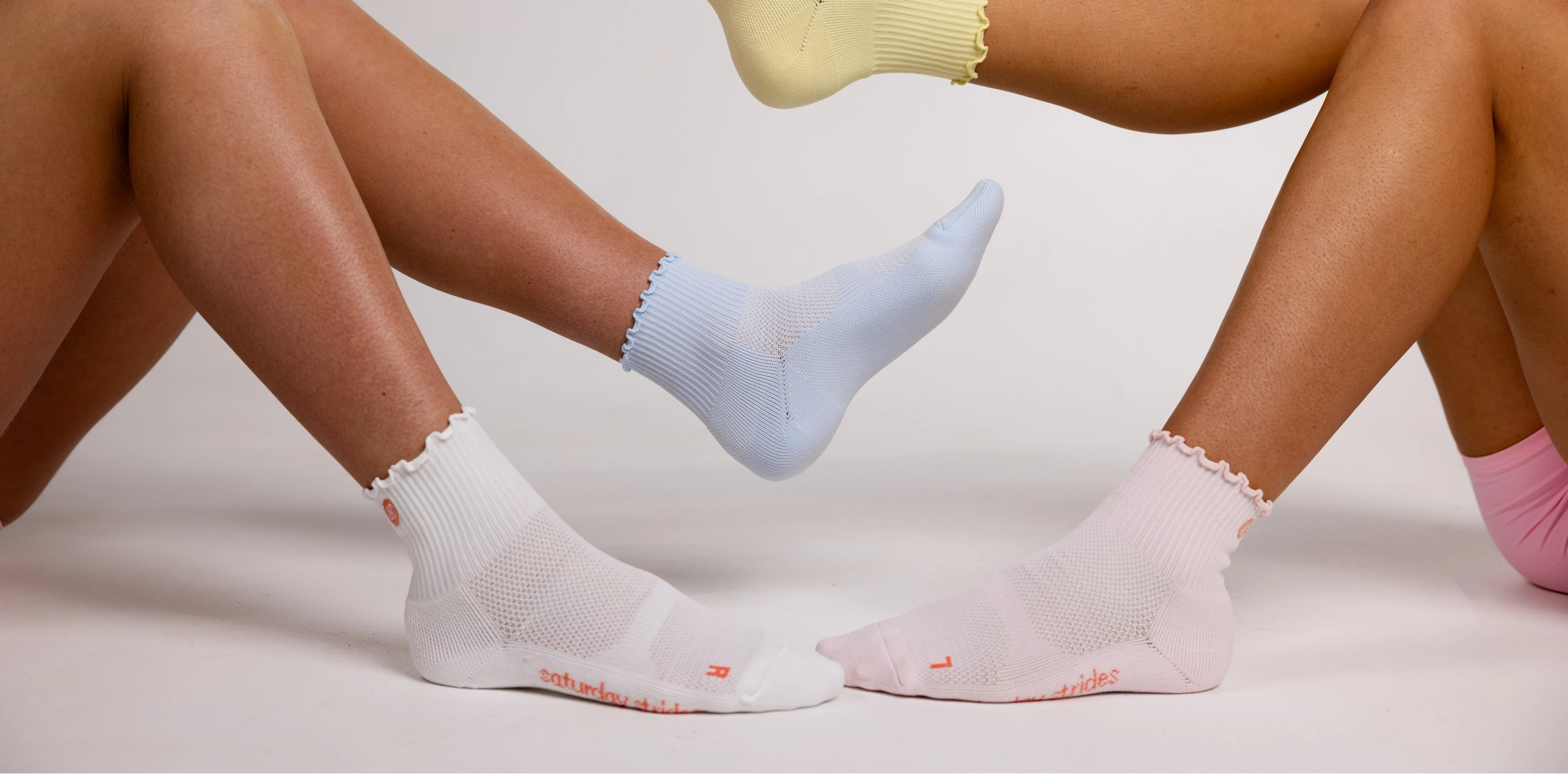 Two pairs of legs wearing colorful socks on a plain background