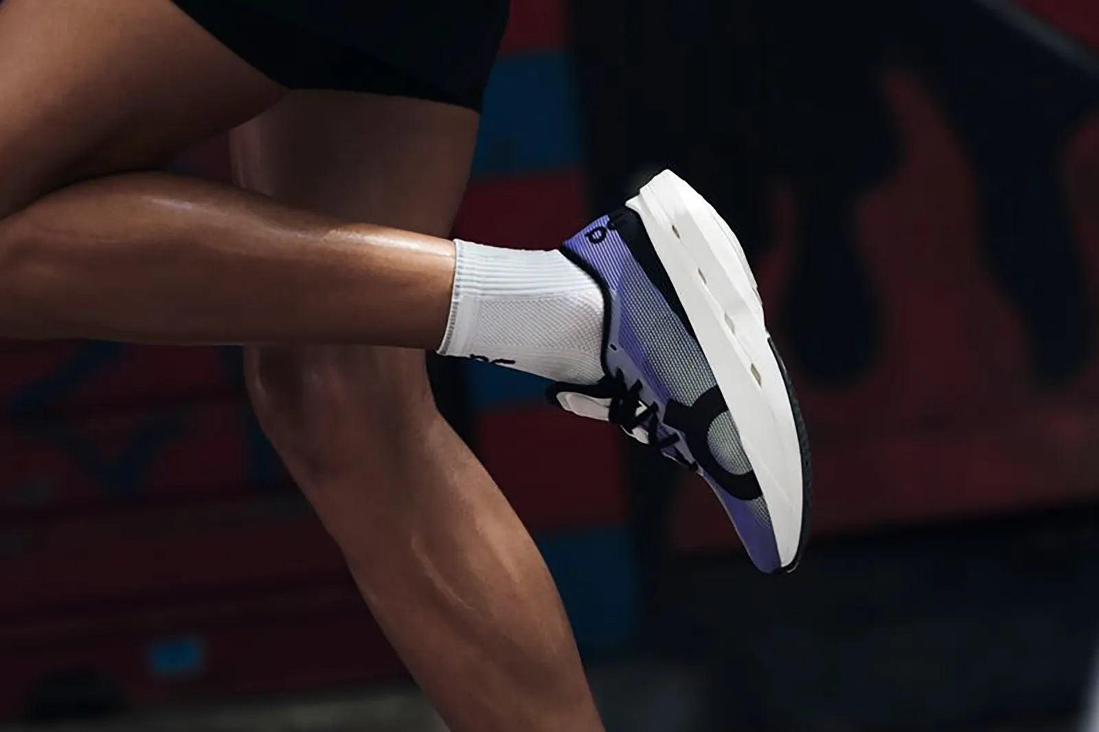 Person wearing a black and white athletic shoe with a colorful background